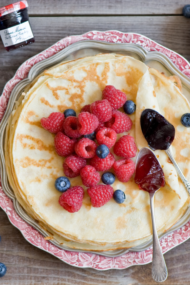 Тонкие блины с малиной и черникой на столе вид сверху