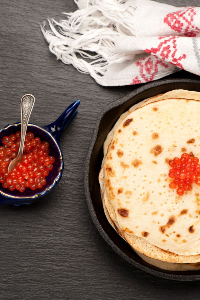 Тонкие блины с красной икрой на столе вид сверху