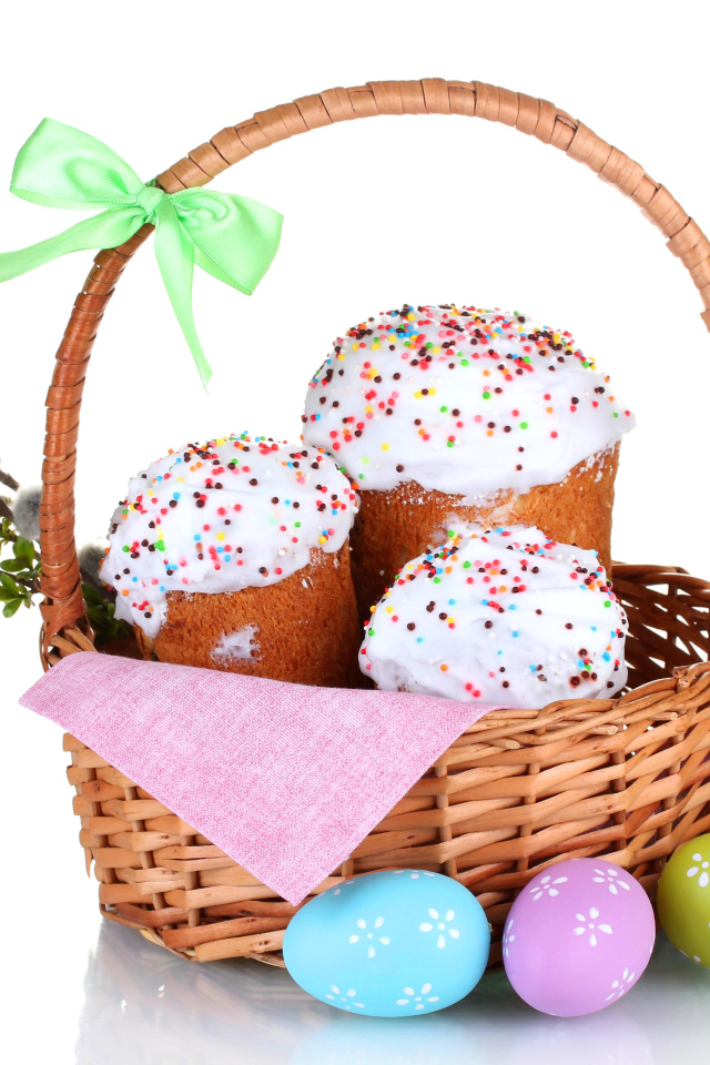 Пасхальные куличи в корзине с крашеными яйцами на белом фоне