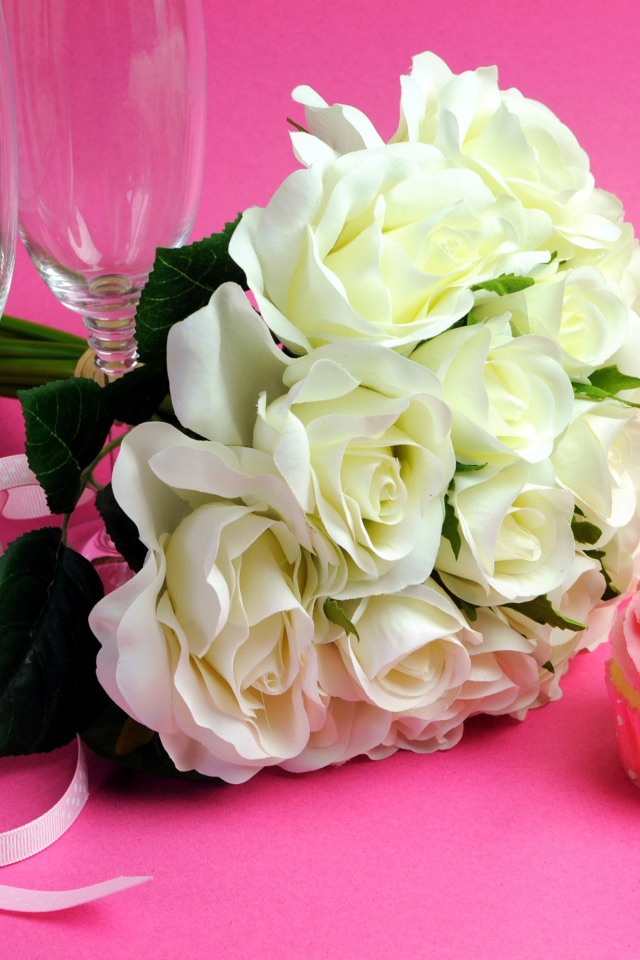 Букет белых роз, пирожное и два бокала на розовом фоне на 8 марта