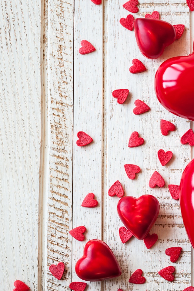 Большие и маленькие  красные  сердечки на деревянном фоне