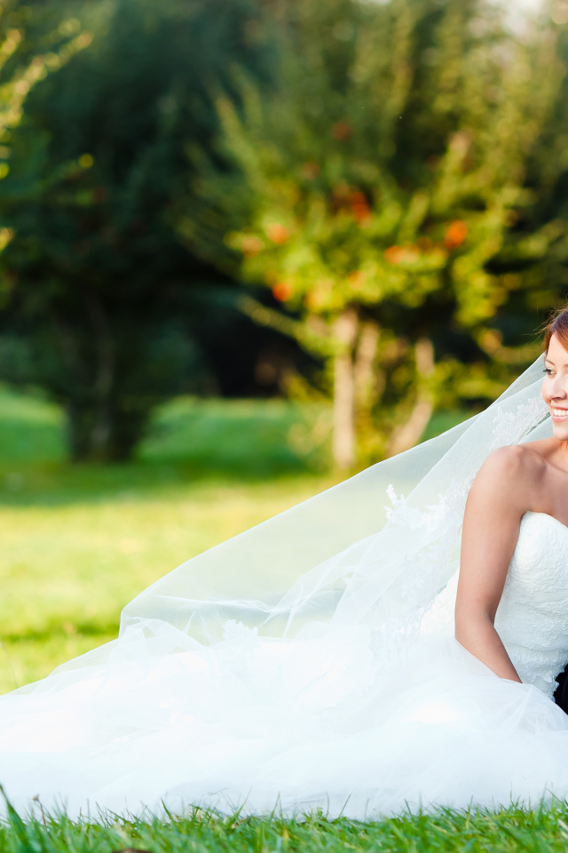 Счастливые жених и невеста сидят на зеленой траве