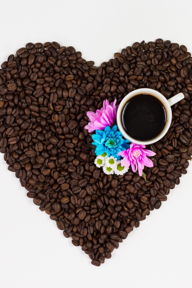 Сердце из кофейных зерен с чашкой на белом фоне