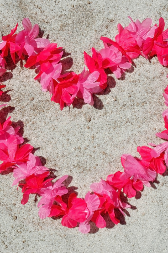 Сердце из розовых цветов на песке