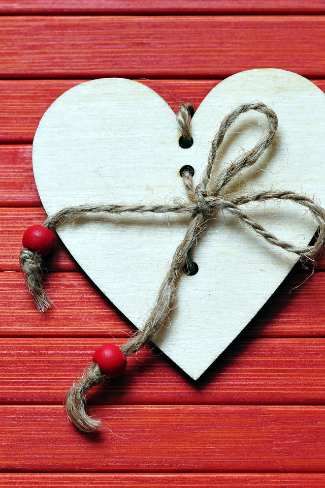 Сердце с веревкой на красном деревянном фоне