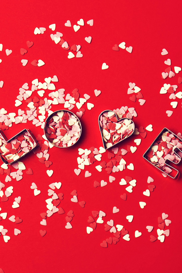 Надпись любовь из маленьких  сердечек на красном фоне