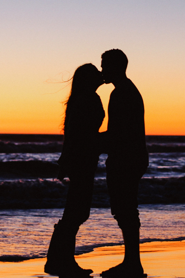 Поцелуй влюбленной пары на берегу моря на закате 