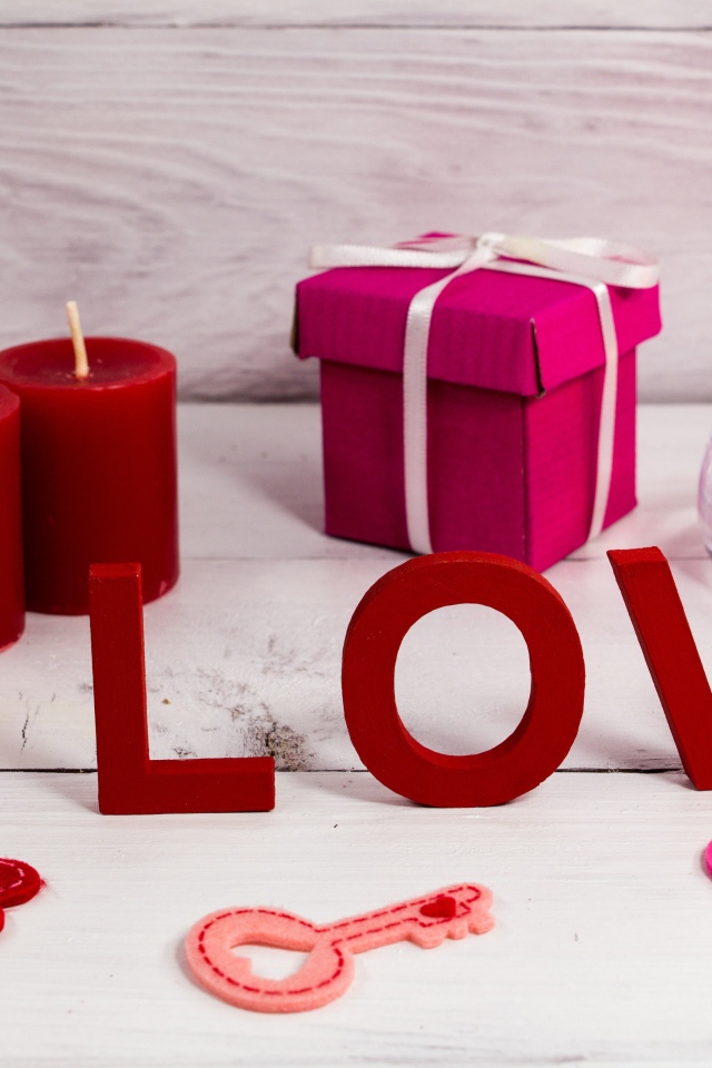 Надпись любовь на столе с красными свечами и подарком