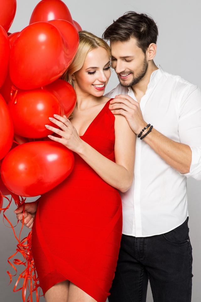 Влюбленная пара с красными воздушными шарами в форме сердца