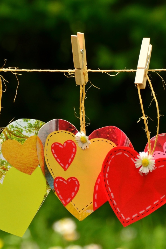 Бумажные сердечки висят на веревке на прищепках