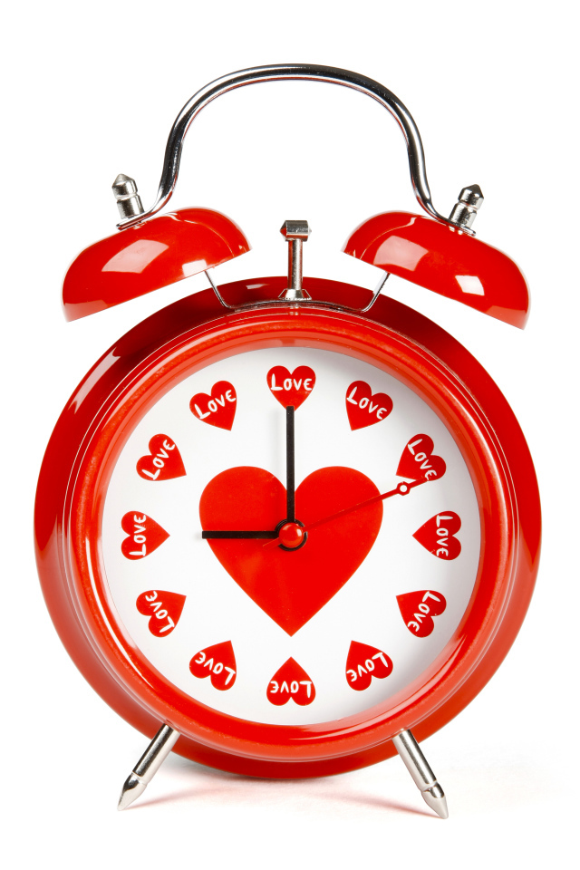Красный будильник с сердечками на белом фоне