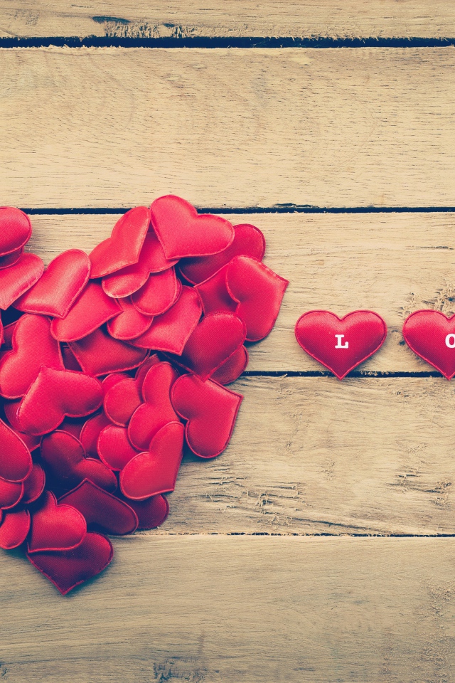 Маленькие красные сердечки на деревянной поверхности 