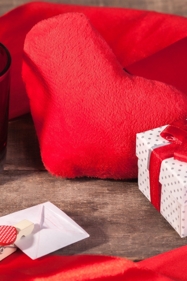 Мягкое красное сердце на столе с подарком и зажженной свечей