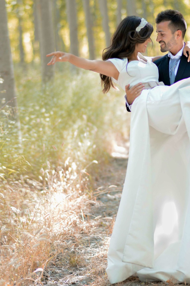 Парень жених держит на руках невесту в белом платье