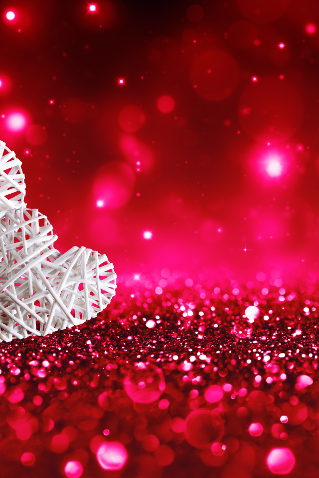 Два белых плетеных сердца на мерцающем красном фоне