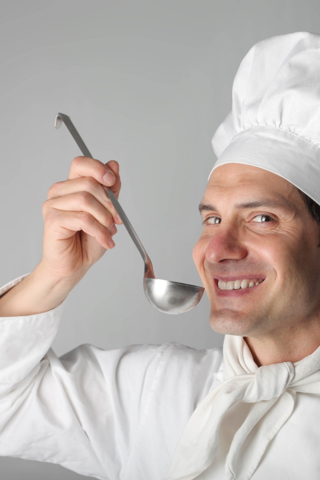 Улыбающийся мужчина повар с половником в руках на сером фоне