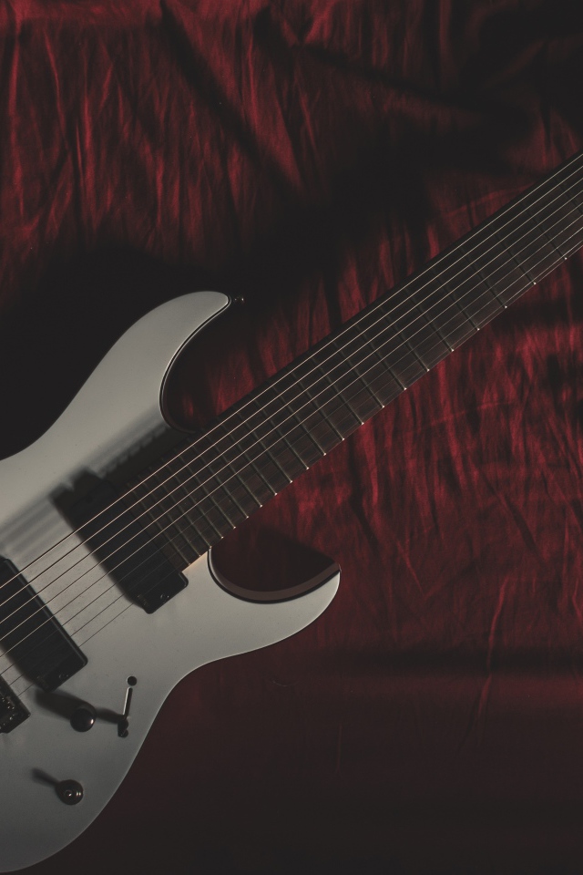 Гитара лежит на красном покрывале