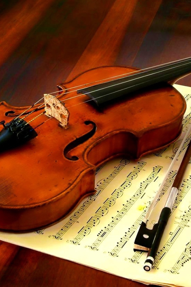 Скрипка со смычком лежат на нотной тетради
