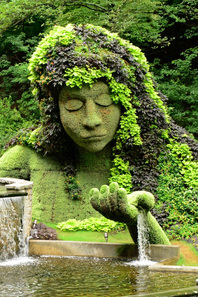 Красивый водопад в парке со скульптурой 