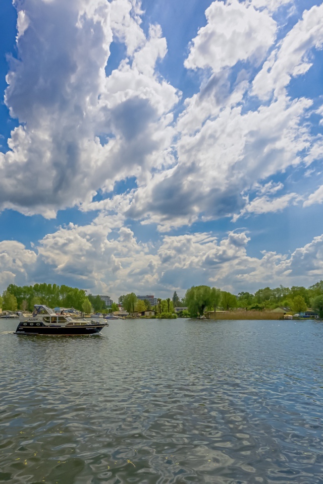 Катер на озере под красивым голубым небом с белыми облаками