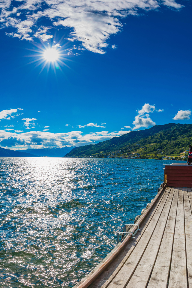 Яркое солнце в голубом небе над водой, Исландия