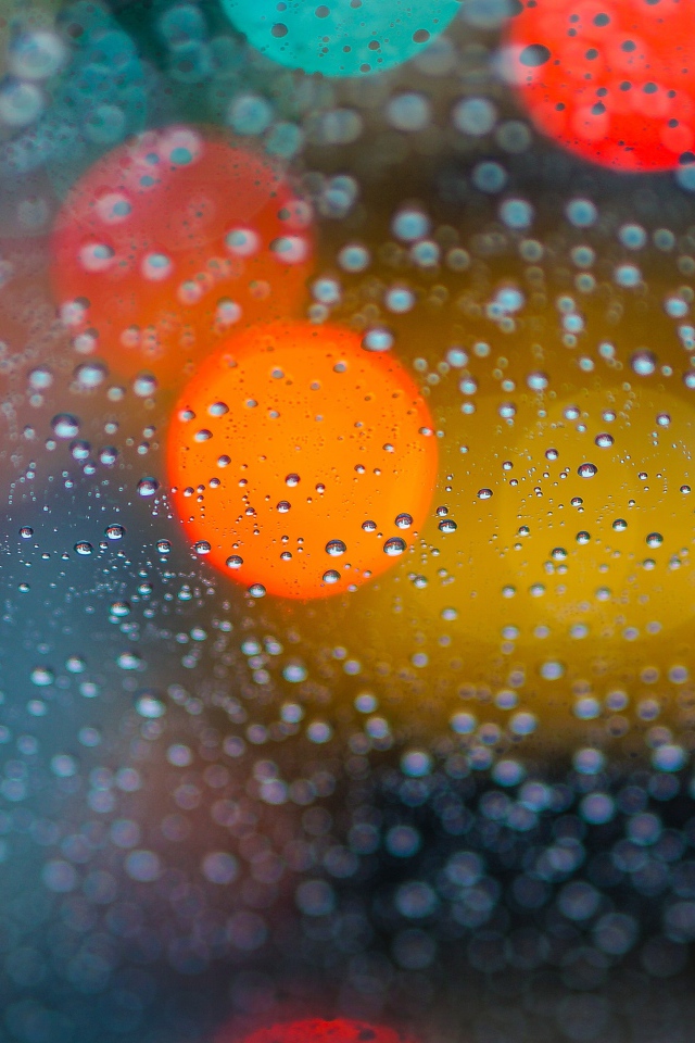 Капли дождя на стекле с разноцветными бликами