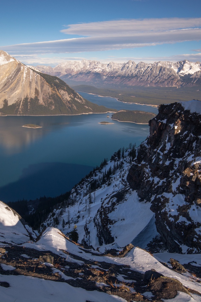 Озеро между заснеженных гор на фоне голубого неба