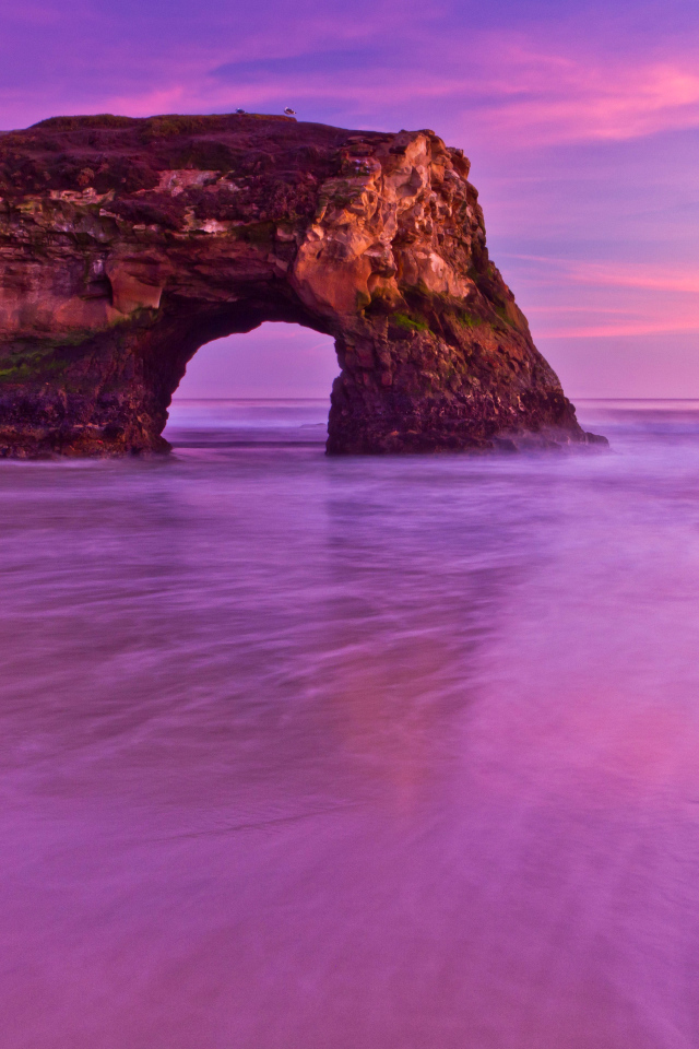 Гора с аркой в океане на фоне красивого неба