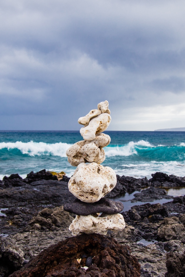 Пирамида из камней у моря на фоне пасмурного неба