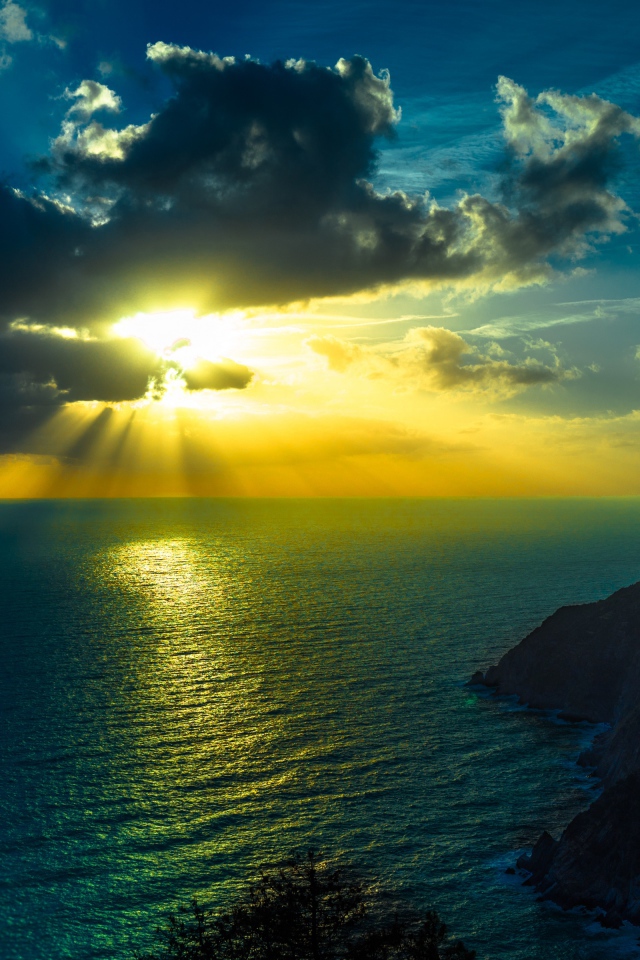 Лучи яркого солнца пробиваются сквозь облака над морем