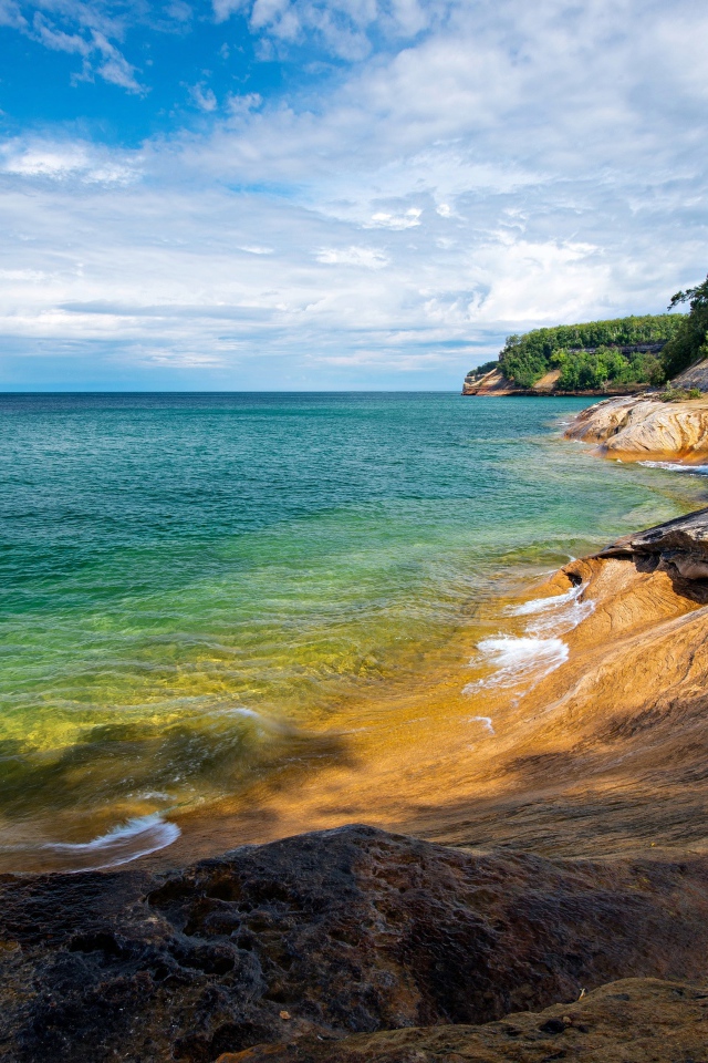 Скалистый берег у голубой воды моря на фоне неба