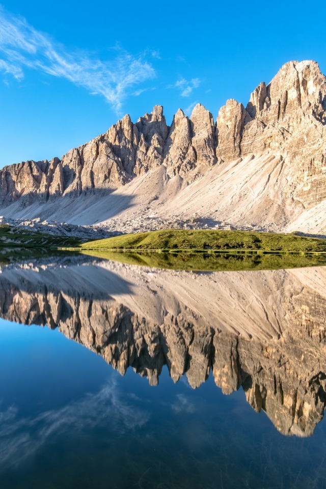 Горы и голубое небо отражаются в чистой воде 