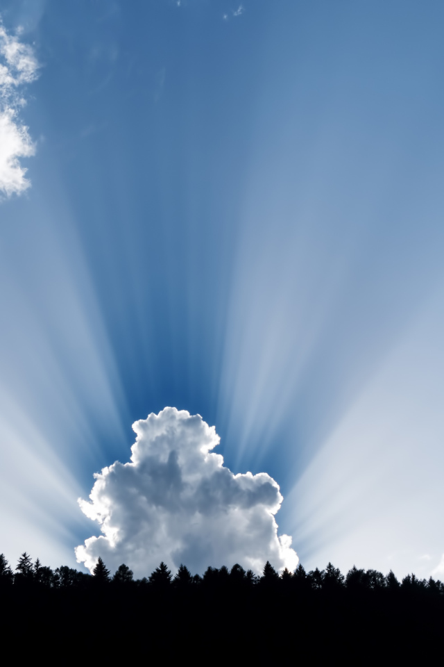 Лучи солнца пробиваются сквозь белые облака в голубом небе 