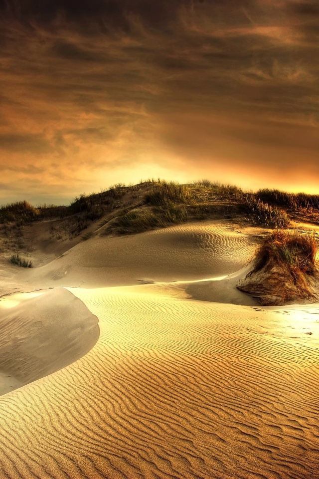 Волнистый песок под красивым небом на закате