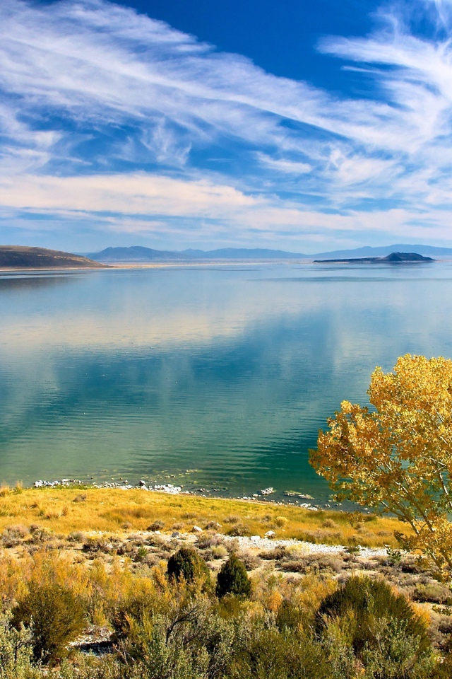 Белые облака в голубом небе отражаются в озере