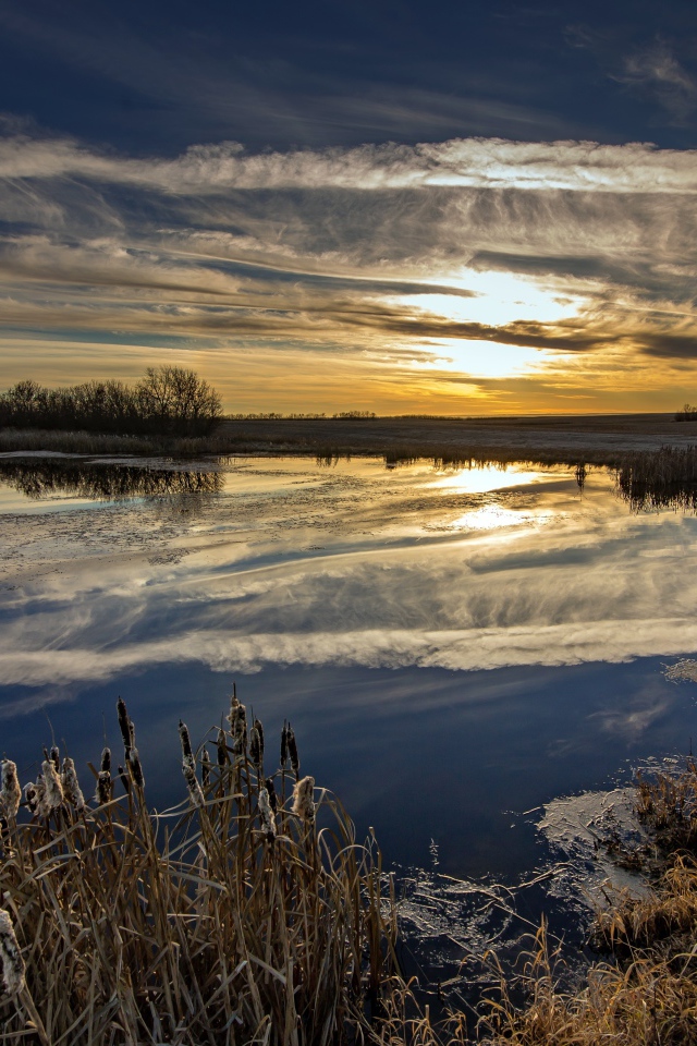 Белые облака отражаются в воде на закате солнца