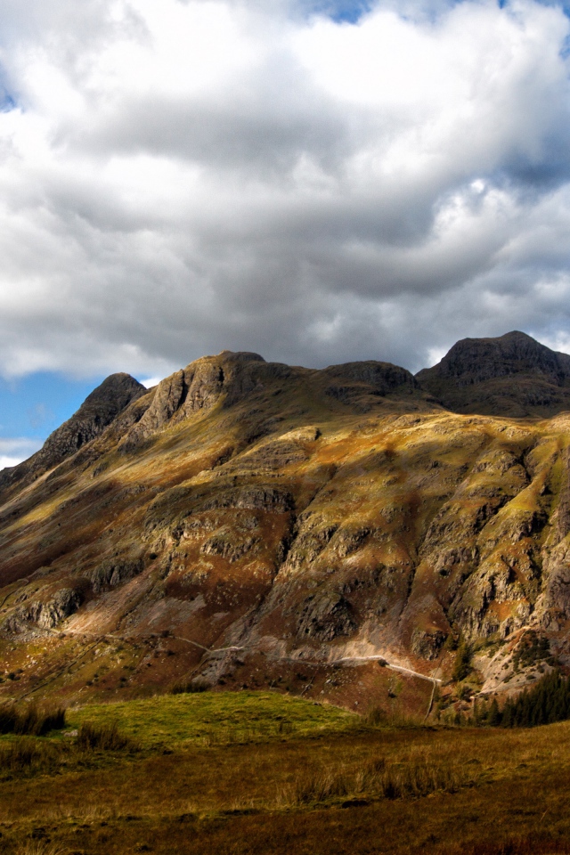 Белые пушистые облака над горой 