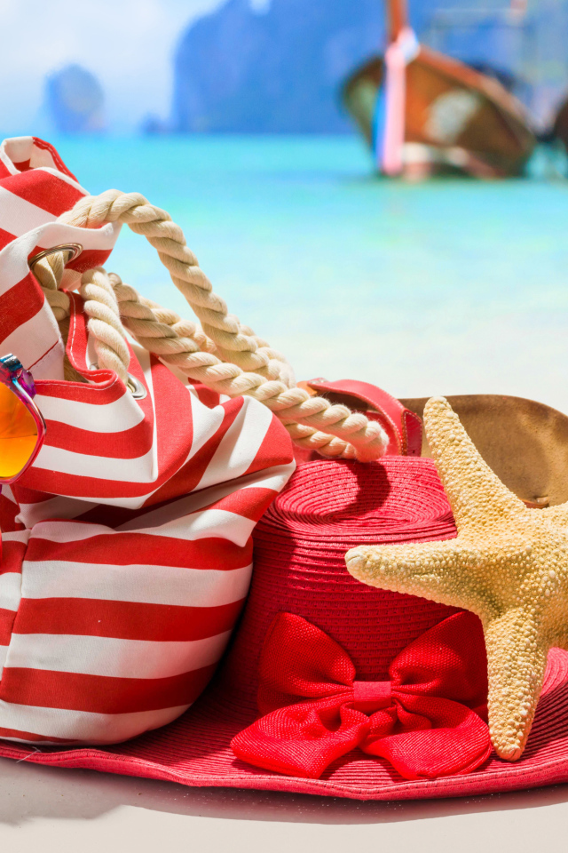 Большая красная шляпа с сумкой и морской звездой на пляже