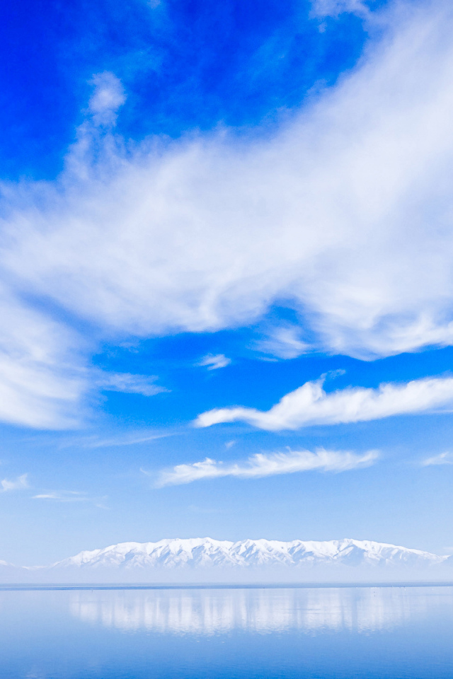 Красивые белые облака над водой около заснеженных гор
