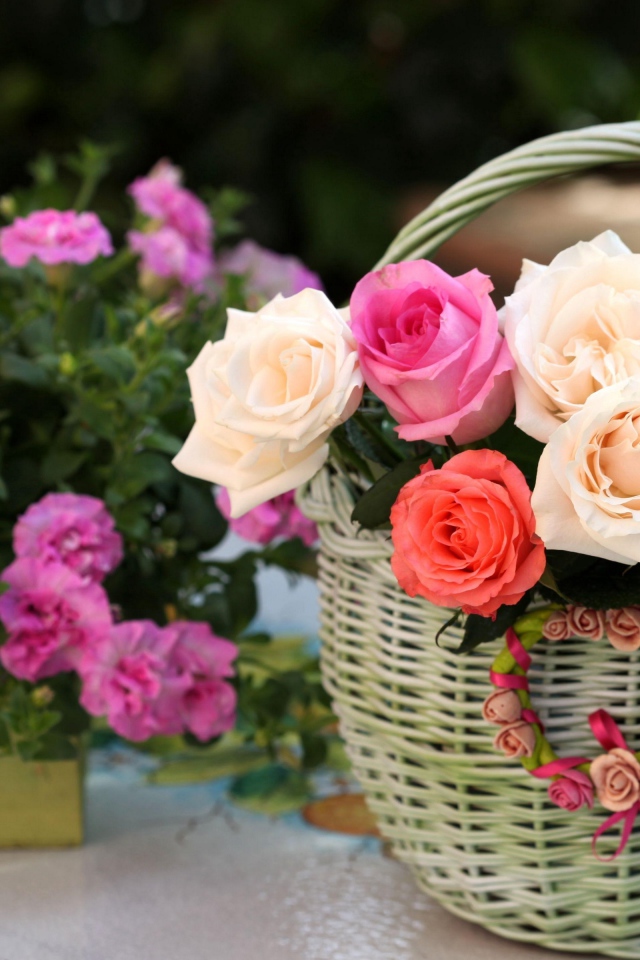 Букет нежных роз в корзине на столе с цветами