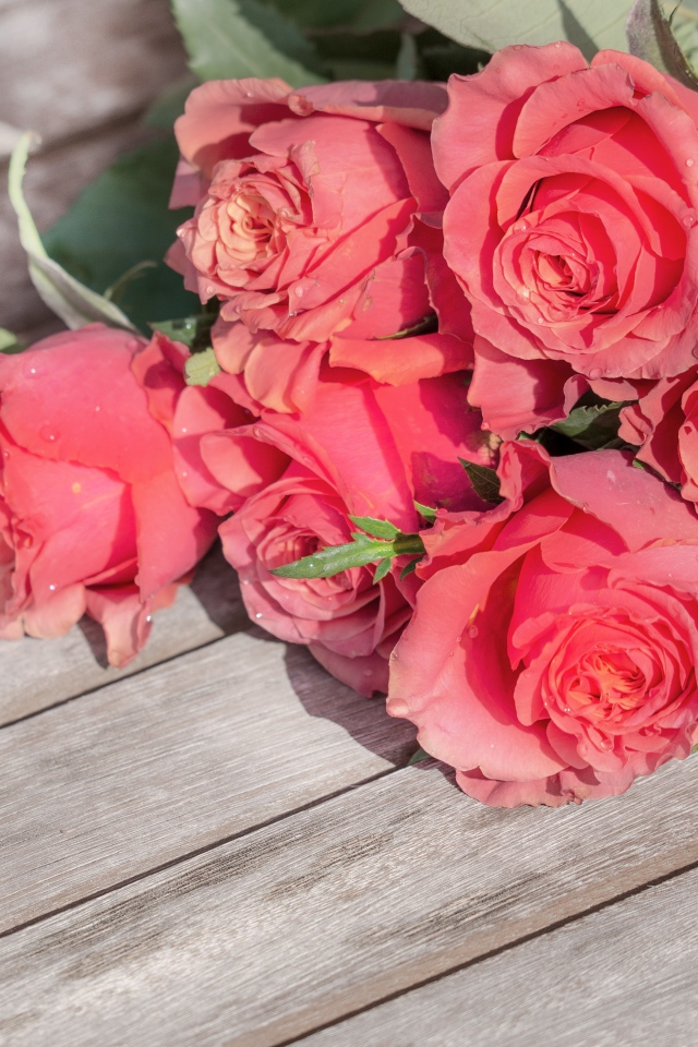 Букет розовых роз лежит на деревянной поверхности