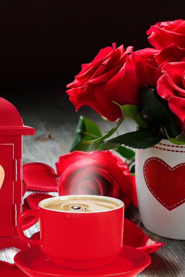 Букет красных роз в чашке на столе с фонариком и чашкой кофе