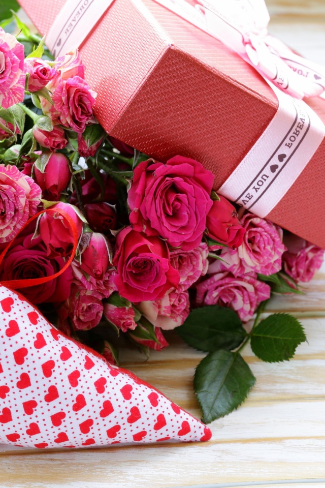 Букет розовых роз с подарком и сердечком на столе