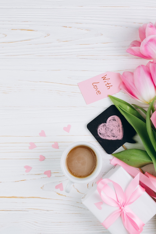 Букет розовых тюльпанов на столе с чашкой кофе и подарком 