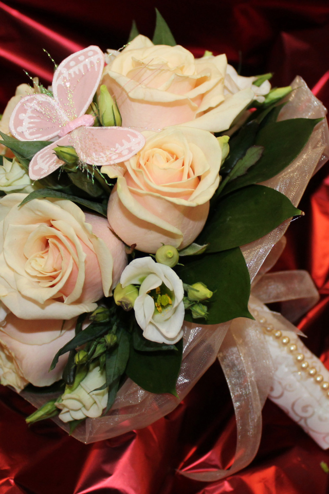 Нежный свадебный букет с цветами розовой розы и эустомы на красном фоне