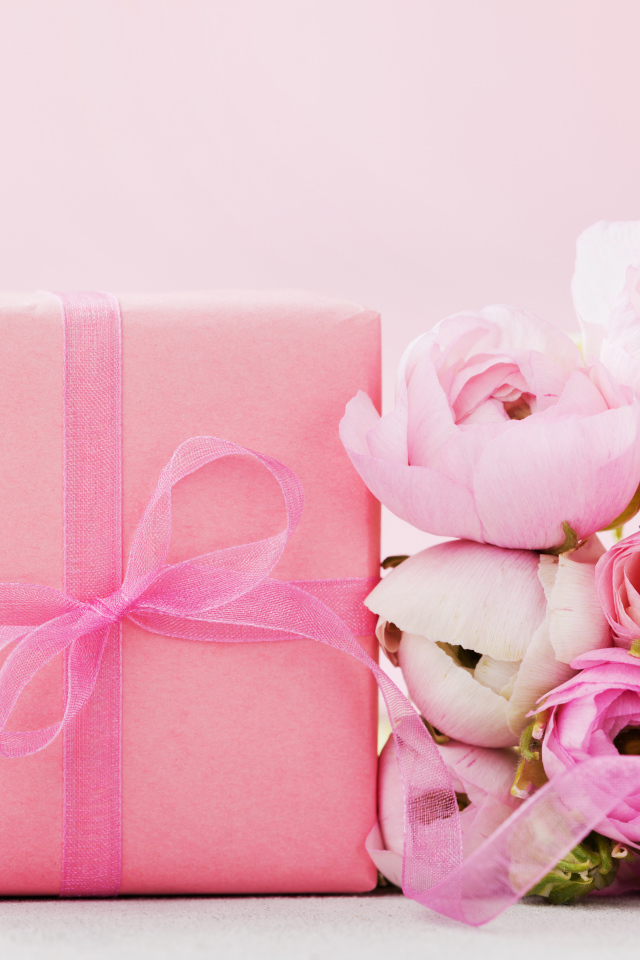 Розовый подарок с букетом розовых лютиков на розовом фоне