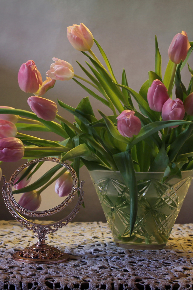 Розовые тюльпаны в стеклянной вазе на столе с зеркалом 