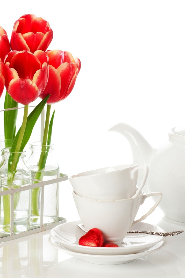 Красные тюльпаны с чайным сервизом на белом фоне