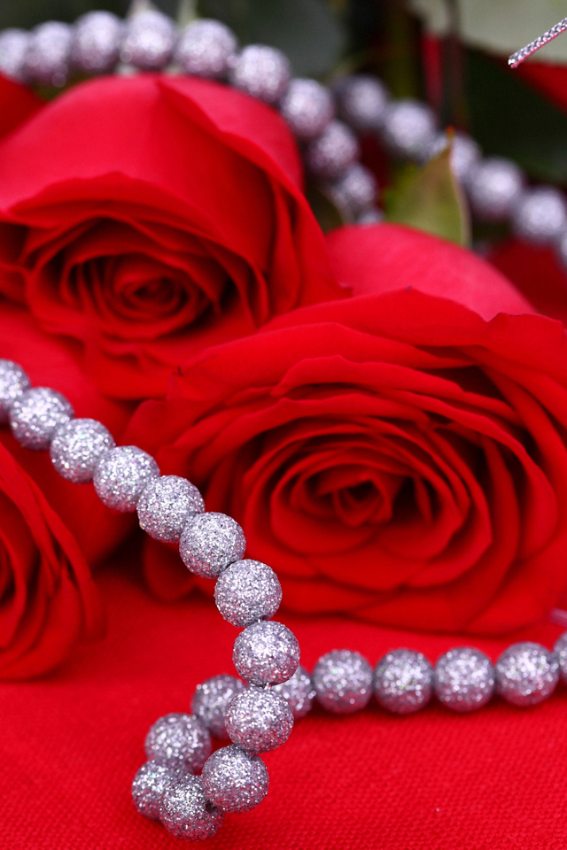 Три красные розы с украшением на красном фоне