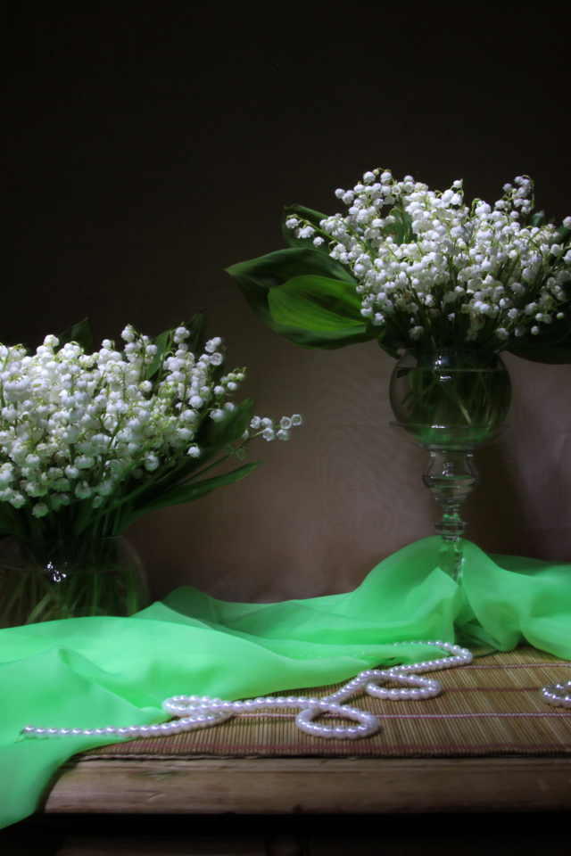Два букета ландышей с бусами на столе 